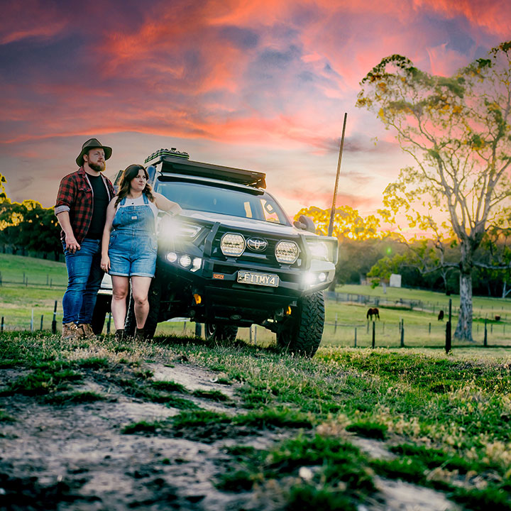 A farming couple beside their four-wheel drive at sunset