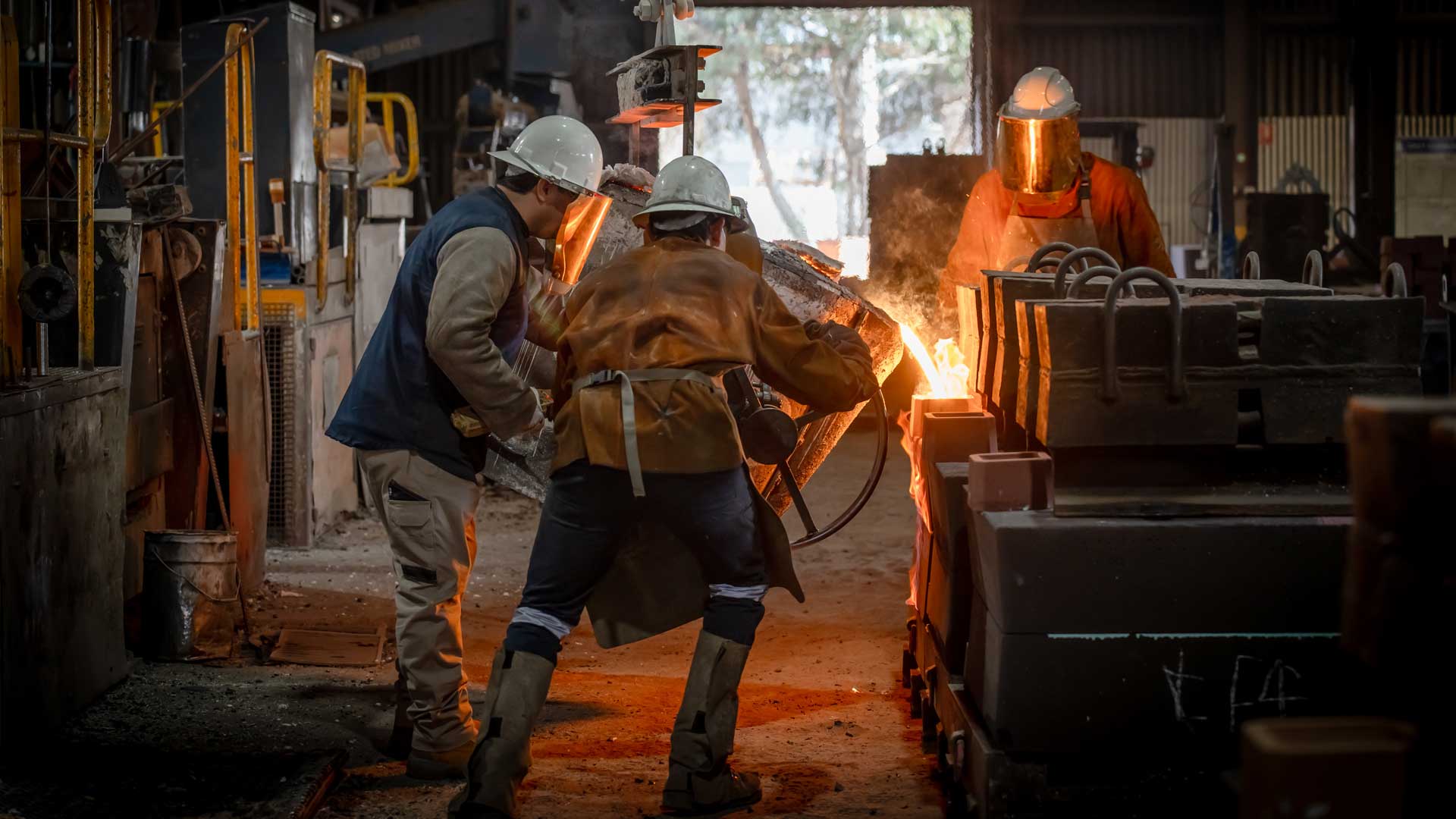 Foundry workers pouring glowing molten metal